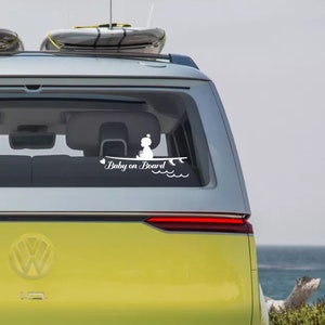 May include: A yellow car with a white sticker on the back window that says "Baby on Board" with a silhouette of a baby sitting on a surfboard. The car has a surfboard on the roof.
