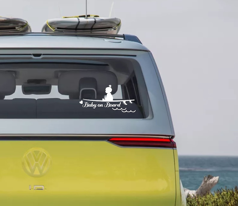 May include: A yellow car with a white sticker on the back window that says "Baby on Board" with a silhouette of a baby sitting on a surfboard. The car has a surfboard on the roof.