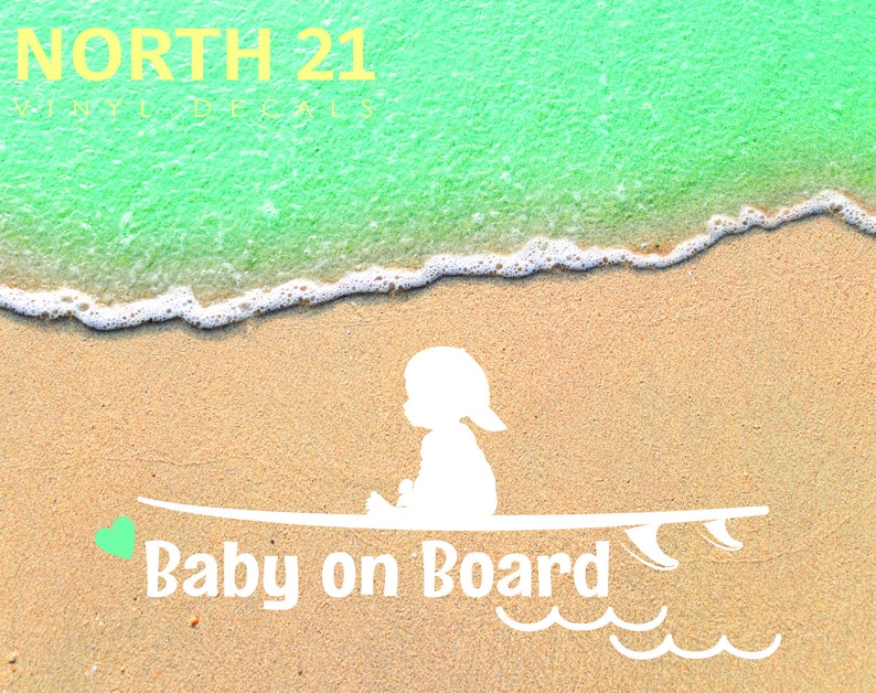 May include: White silhouette of a baby sitting on a surfboard with the text "Baby on Board" and a green heart on the left side of the surfboard. The background is a sandy beach with a turquoise ocean.