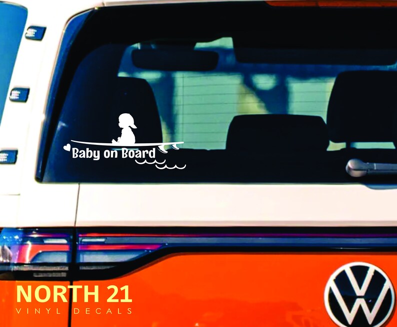 May include: White vinyl decal with a silhouette of a baby sitting on a surfboard with the text "Baby on Board" and a heart. The decal is on the back window of a red car.