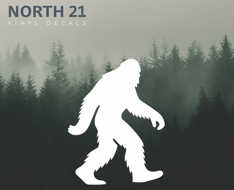 May include: White vinyl decal of a Bigfoot silhouette walking to the right. The decal is set against a backdrop of a misty forest with evergreen trees. The text "NORTH 21 VINYL DECALS" is at the top left.