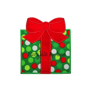 May include: A green square gift with red, white, and green polka dots, topped with a large red bow and ribbon. The gift is outlined in green. The text "Fairy Tale Applique" is printed on the gift.