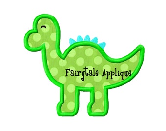 May include: Green dinosaur applique with white polka dots and a blue spiky back. The applique has the text "Fairytale Applique" in black.