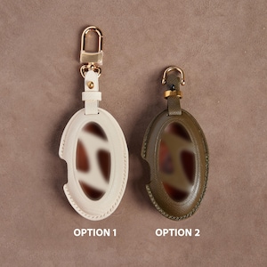 Two oval-shaped keychains with different colors and designs are displayed side by side.