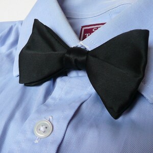 May include: A black bow tie on a light blue dress shirt.
