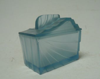 May include: A light blue, Art Deco-style box with a lid and handle. The box has a rectangular shape with a fan-like design on the sides. The lid has a curved handle and a stepped design. The box is made of a translucent material.