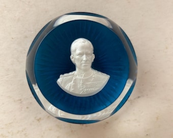 May include: A blue glass paperweight with a white etched image of a man in a military uniform.