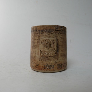 Op de afbeelding: Een bruine keramische mok met de tekst "H.R.H. The Prince of Wales" en "July 1969 Investiture" aan de zijkant.