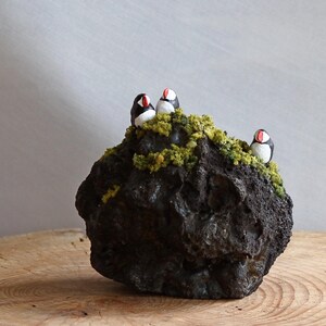 Pequeñas esculturas de frailecillos sobre una roca de lava. Diseño de Ása Valdimarsdóttir
