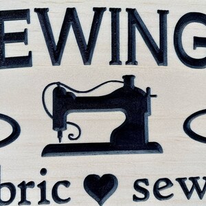 May include: A wooden sign with the text "Sewing is my therapy" and a black silhouette of a sewing machine. The sign also includes a heart and the text "fabric sew love".