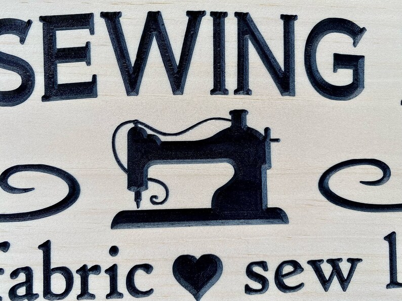 May include: A wooden sign with the text "Sewing is my therapy" and a black silhouette of a sewing machine. The sign also includes a heart and the text "fabric sew love".