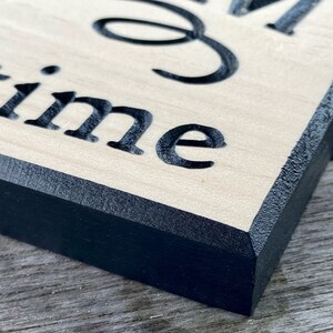 May include: Close-up of a wooden sign with black painted edges. The sign reads "Good times".