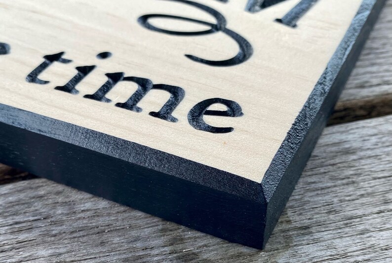May include: Close-up of a wooden sign with black painted edges. The sign reads "Good times".