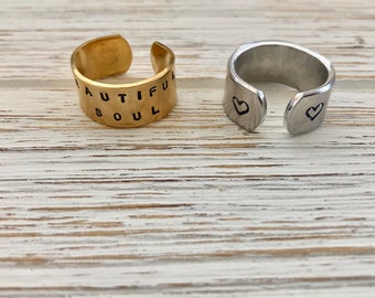 Puede incluir: Dos anillos ajustables, uno dorado con las palabras "Beautiful Soul" grabadas en él, y uno plateado con dos pequeños corazones grabados en él.