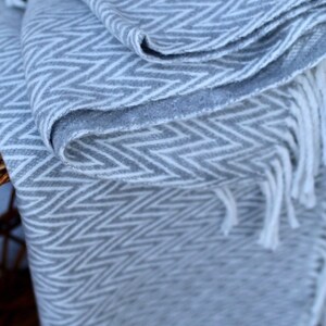 May include: A gray and white chevron patterned throw blanket with white fringe.