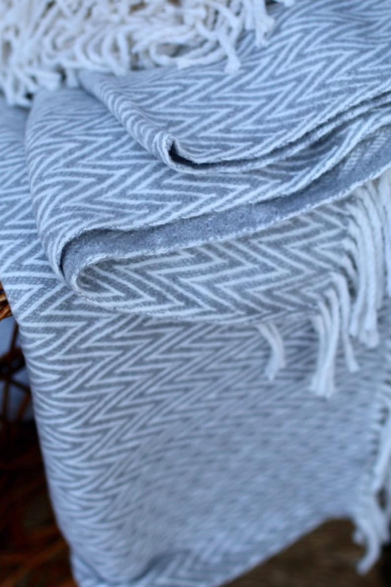 May include: A gray and white chevron patterned throw blanket with white fringe.
