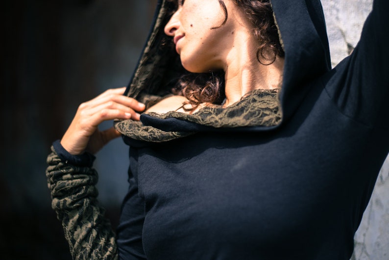 May include: A black hooded top with a lace trim around the neckline. The hood is pulled up and the top is worn over the shoulders.