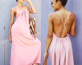 May include: Two women wearing pink maxi dresses. The dress on the left has a halter neckline and the dress on the right has a criss-cross back.