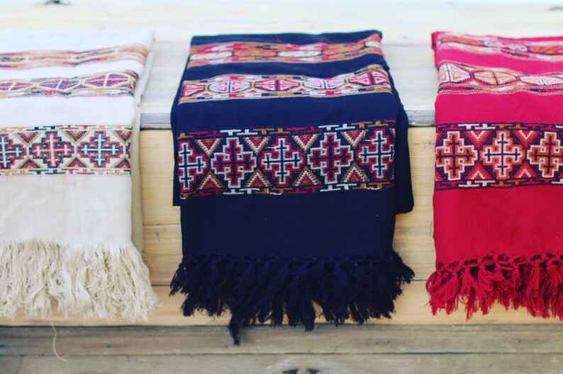 May include: Three woven shawls with fringe, one white, one black, and one red, each with a geometric pattern.