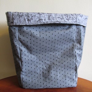 May include: A grey fabric storage bin with a polka dot pattern and a floral print on the top edge.
