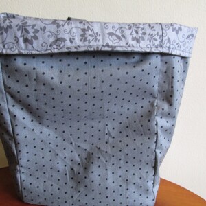 May include: A grey tote bag with a black polka dot pattern and a floral print on the top edge.