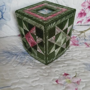 May include: Green and pink tissue box cover with a geometric pattern. The cover is made of plastic canvas and has a square opening for tissues.