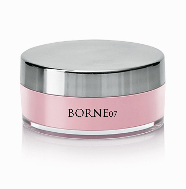 Pode incluir: Um recipiente redondo de p&oacute; facial rosa com tampa prateada e o texto "BORNE07" impresso na frente.