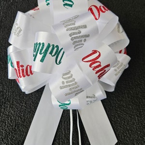 May include: White satin ribbon bow with the words "Happy Birthday" in green glitter, "Dahlia" in red glitter, and "Dahlia" in silver glitter.