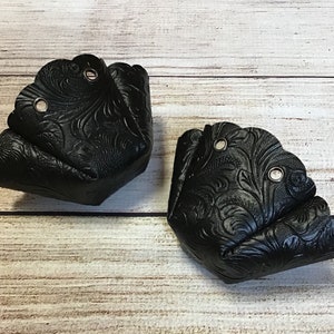May include: Two black leather boot shapers with a floral embossed design. Each shaper has two metal eyelets.