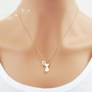 May include: A gold-colored necklace featuring a cat pendant with a small circular charm. The cat pendant is white with gold-colored details. The necklace is worn against a white shirt. The text "Zoe River Elegance" is in the upper left corner.