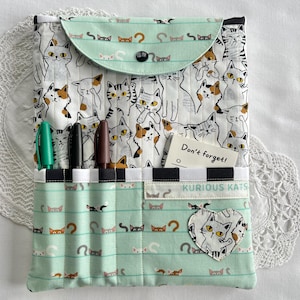 May include: A white ceramic mug with a black handle and the text "But First, Coffee" in a black, bold font. The mug is sitting on a wooden surface. The mug is approximately 4 inches tall.