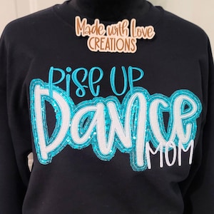 May include: Black sweatshirt with turquoise and white glitter lettering that reads "Rise Up Dance Mom".