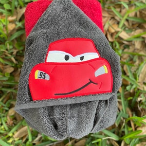 May include: Gray hooded towel with a red car face embroidered on the front. The car has a yellow number 95 on the side.