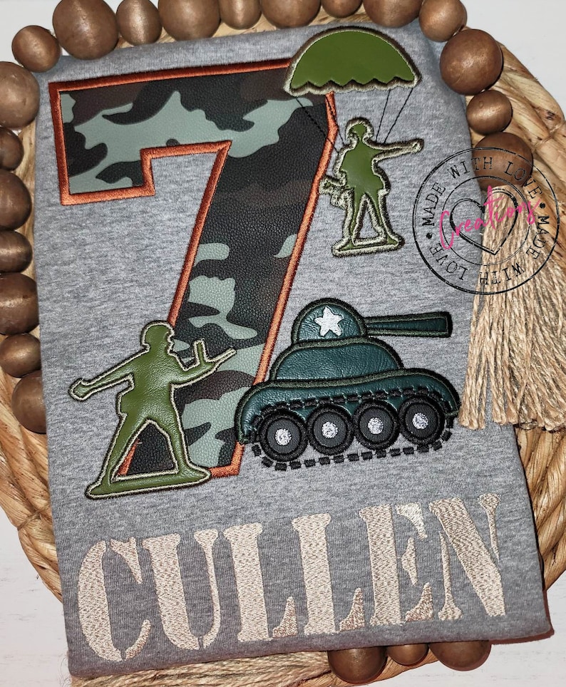 May include: A gray t-shirt with a camouflage number seven, a green toy soldier, a green toy tank, and a green parachute soldier. The text "CULLEN" is embroidered below the design.