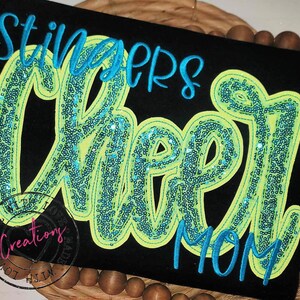 May include: Black t-shirt with the words "Stingers Cheer Mom" in turquoise and neon green with sequins.