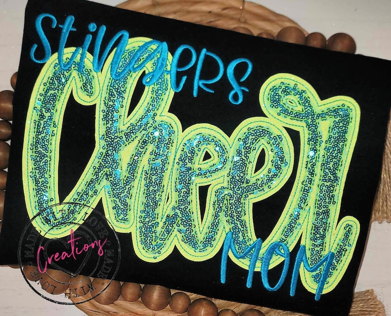 May include: Black t-shirt with the words "Stingers Cheer Mom" in turquoise and neon green with sequins.