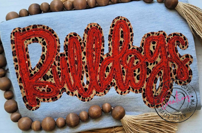 May include: Red and black glitter iron-on patch with the word "Bulldogs" in a cursive font. The patch has a leopard print design.