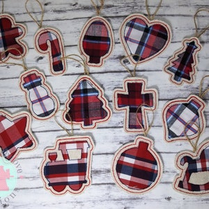 May include: Twelve Christmas ornaments made of red and blue plaid fabric. The ornaments are in the shapes of a gingerbread man, candy cane, Christmas tree, heart, snowman, star, cross, bell, train, ornament, and rocking horse.
