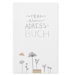 Könnte beinhalten: Ein weißer Notizbuchumschlag mit schwarzem handschriftlichem Text, der "Mein kleines Adress-Buch" lautet, und einer Schwarzweißillustration von Blumen und einer Wolke.