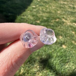 May include: A pair of clear glass paw print earrings with pink and purple accents.