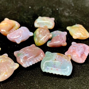 May include: A collection of ten small, carved agate stones in the shape of cartoon cats. The stones are a mix of pink, white, and brown with a mottled pattern.