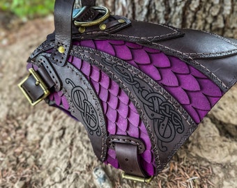May include: A purple leather dog harness with a decorative Celtic knot design and a brown leather handle. The harness is made of high-quality leather and features a durable buckle.