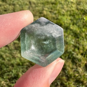 May include: A light green hexagonal crystal with a smooth, polished surface. The crystal is translucent and has a slight shimmer.