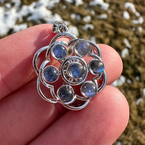 May include: Silver pendant with a flower design featuring six iridescent blue labradorite gemstones.