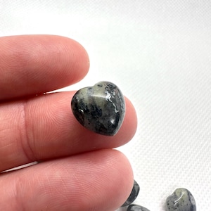 May include: A collection of small, heart-shaped stones with a black and white marbled pattern.