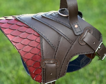 May include: A brown and red leather dog harness with a dragon scale design. The harness features a handle, metal ring, and adjustable buckles. The red scales transition to brown leather with decorative stitching.