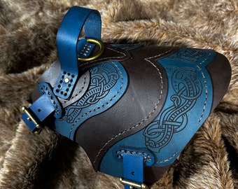 May include: A brown leather dog collar with blue leather accents and a brass buckle. The collar is decorated with a blue and brown Celtic knot design.