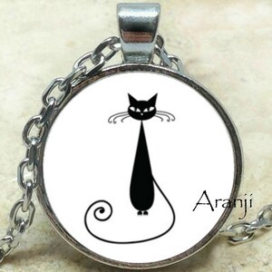 May include: A silver chain necklace with a round glass pendant featuring a black silhouette of a cat with a curled tail. The pendant has a white background and the word "Aranji" is printed in the bottom right corner.