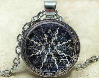 May include: A silver chain necklace with a round glass pendant featuring a vintage compass design with a sunburst motif and the text "MERIDIES" and "OCCIDENS".