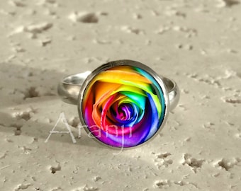 May include: A silver ring with a rainbow rose design. The rose is a vibrant mix of red, orange, yellow, green, blue, and purple.